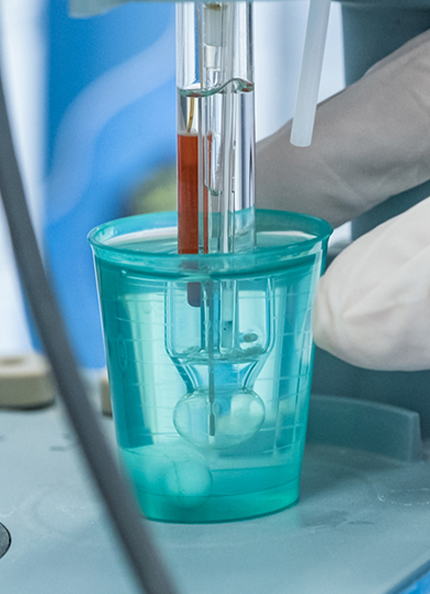 zoom su una mano che tiene in mano una provetta di laboratorio vicino a dei macchinari